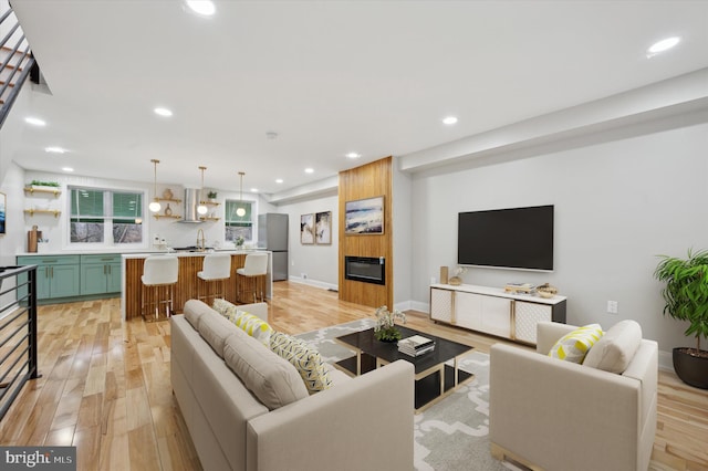 living room featuring sink, light hardwood / wood-style flooring, and a large fireplace