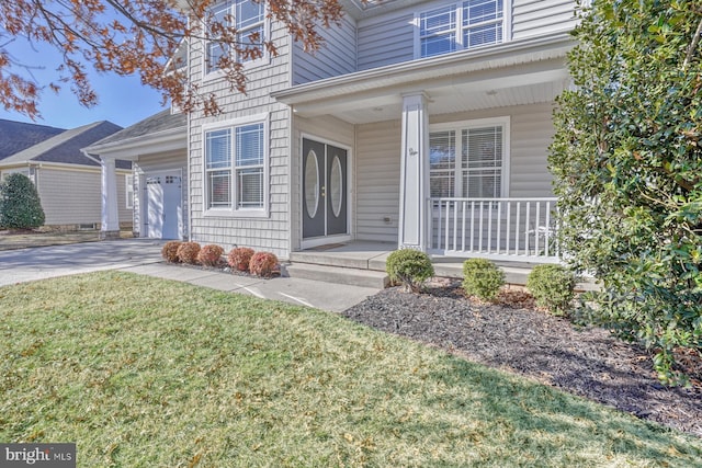 doorway to property with a porch, a garage, and a yard