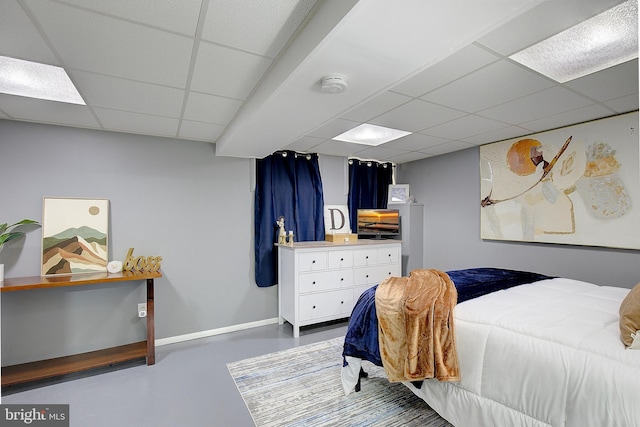 bedroom with a paneled ceiling and concrete floors