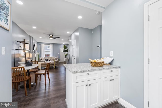 kitchen featuring ceiling fan, dark wood-type flooring, white cabinets, and light stone counters