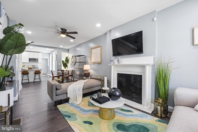 living room featuring ceiling fan and dark hardwood / wood-style flooring