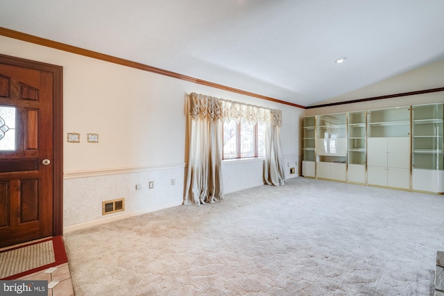 spare room featuring lofted ceiling, crown molding, and light colored carpet