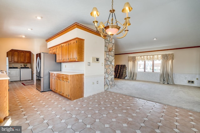 kitchen featuring stainless steel refrigerator, decorative light fixtures, ornamental molding, light colored carpet, and washing machine and clothes dryer