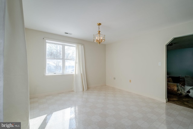 unfurnished room with a notable chandelier