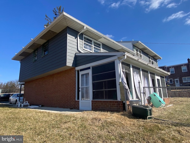 view of home's exterior with central AC unit, a yard, and a sunroom