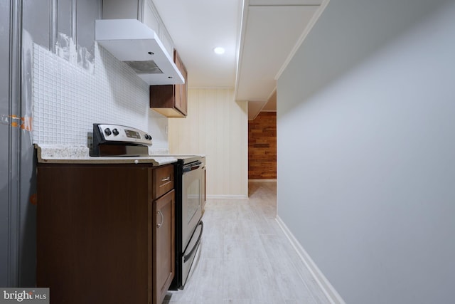 kitchen with stainless steel electric stove, wood walls, dark brown cabinetry, and light hardwood / wood-style floors