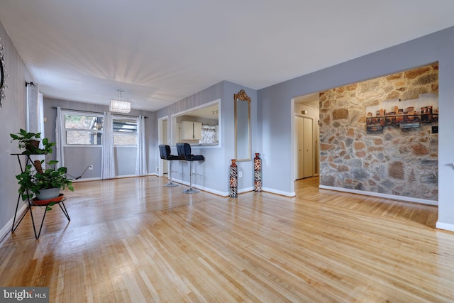 unfurnished living room featuring a notable chandelier and light hardwood / wood-style flooring