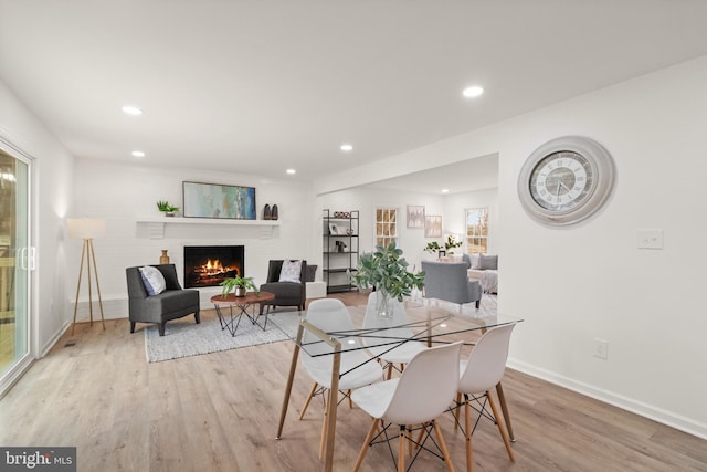 dining area with light wood-style flooring, a fireplace, baseboards, and recessed lighting