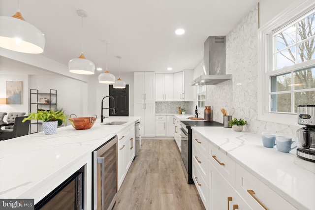 kitchen with tasteful backsplash, range with electric cooktop, wine cooler, wall chimney range hood, and a sink