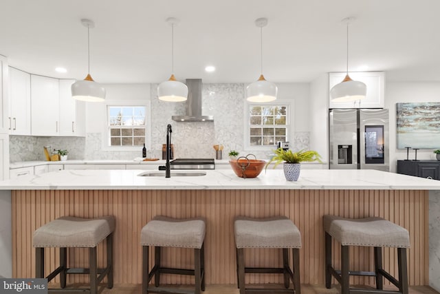 kitchen with plenty of natural light, wall chimney exhaust hood, backsplash, and stainless steel fridge with ice dispenser