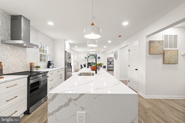 kitchen featuring a center island with sink, visible vents, white cabinets, wall chimney exhaust hood, and stainless steel appliances