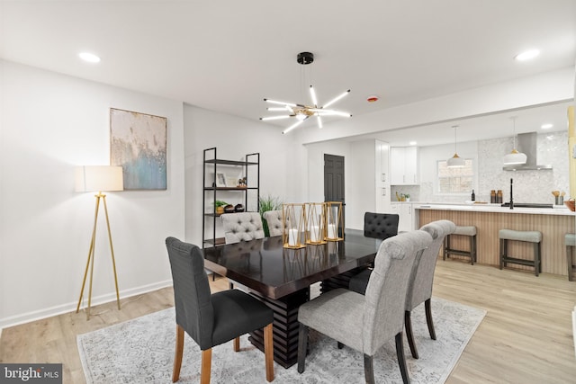 dining space featuring light wood-style floors, recessed lighting, a notable chandelier, and baseboards