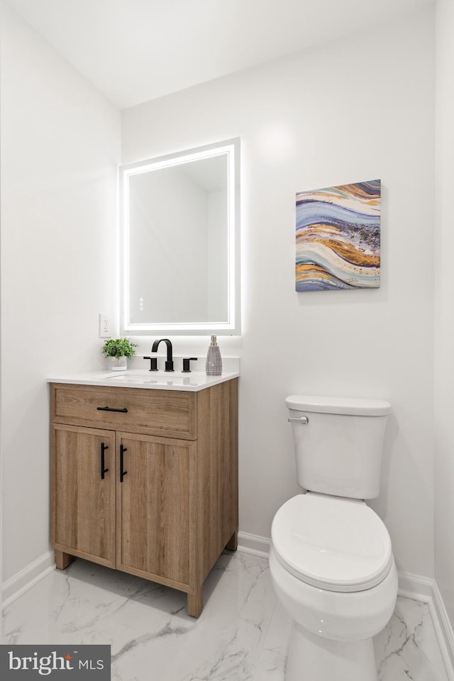 half bath with marble finish floor, toilet, and baseboards