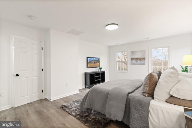 bedroom with wood finished floors, visible vents, and baseboards