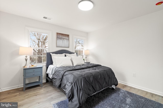 bedroom featuring wood finished floors, visible vents, and baseboards