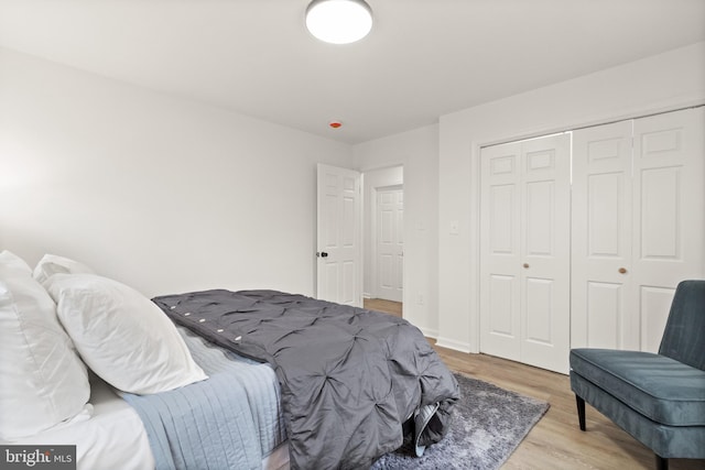 bedroom featuring light wood-type flooring, baseboards, and a closet