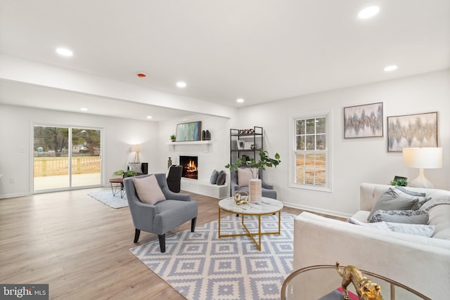 living area featuring light wood-type flooring, a fireplace, baseboards, and recessed lighting