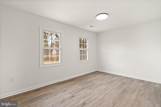 unfurnished room with light wood-style flooring, visible vents, and baseboards