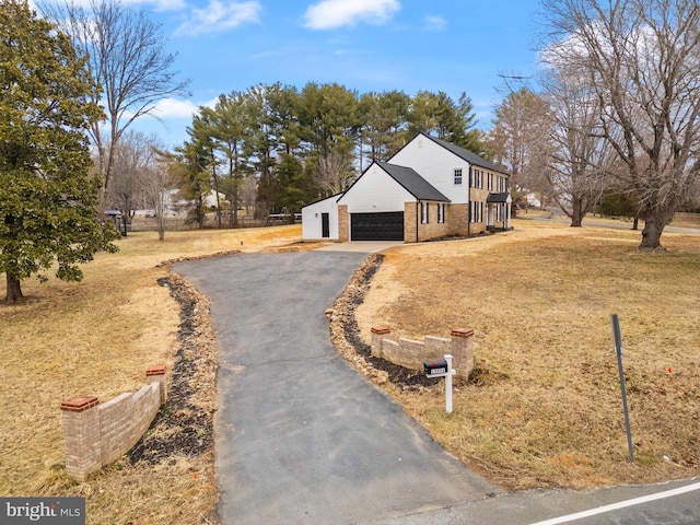 view of front of house with driveway, a front yard, a garage, and brick siding