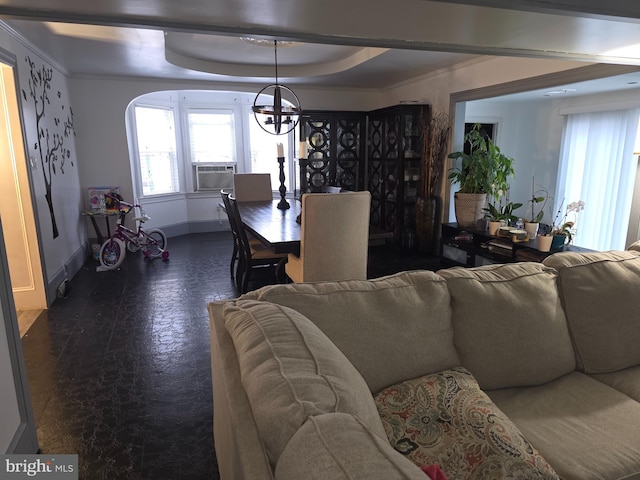 living room with cooling unit, ornamental molding, a raised ceiling, and an inviting chandelier