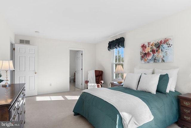 bedroom with light carpet and ensuite bath