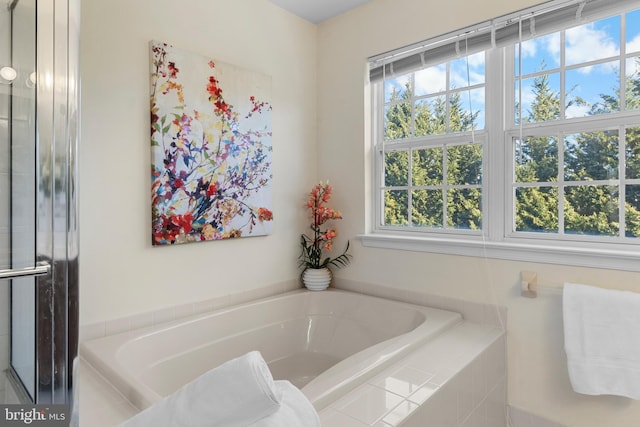 bathroom featuring tiled bath and a wealth of natural light