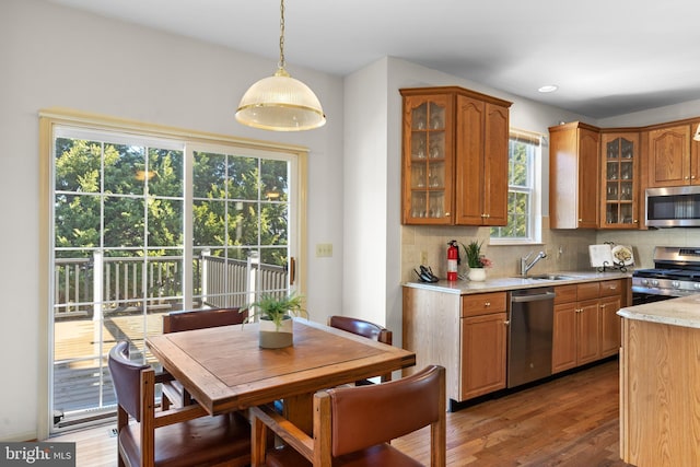 kitchen with sink, hanging light fixtures, stainless steel appliances, light stone countertops, and backsplash