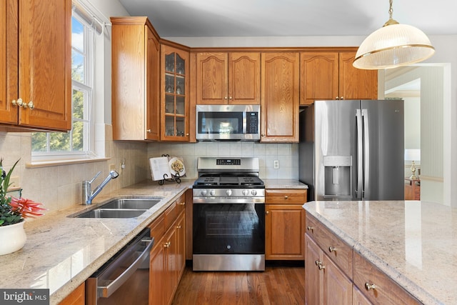 kitchen featuring sink, appliances with stainless steel finishes, light stone counters, dark hardwood / wood-style flooring, and decorative light fixtures