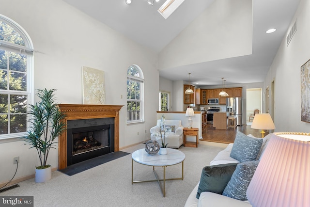 living room with a skylight and high vaulted ceiling