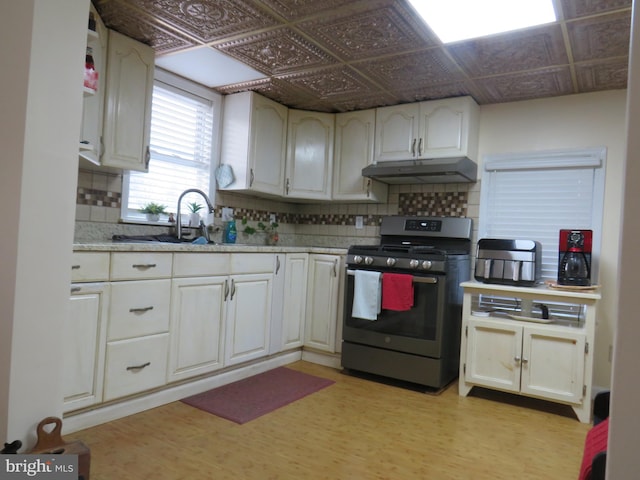 kitchen featuring white cabinetry, sink, stainless steel gas range, and decorative backsplash