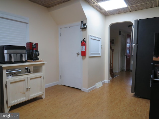 kitchen featuring white cabinets, stainless steel refrigerator, and light hardwood / wood-style flooring