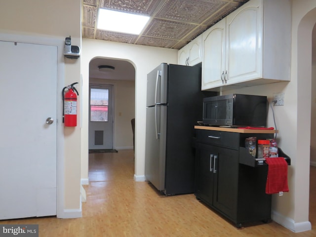 kitchen with white cabinetry, stainless steel fridge, and light hardwood / wood-style flooring