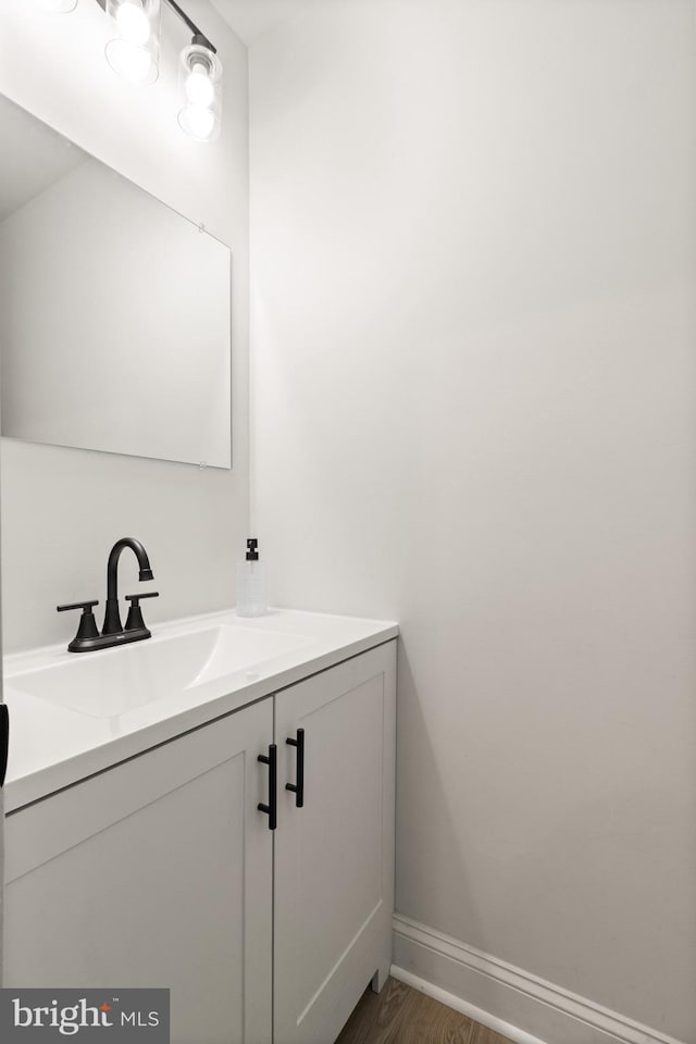 bathroom featuring baseboards, wood finished floors, and vanity