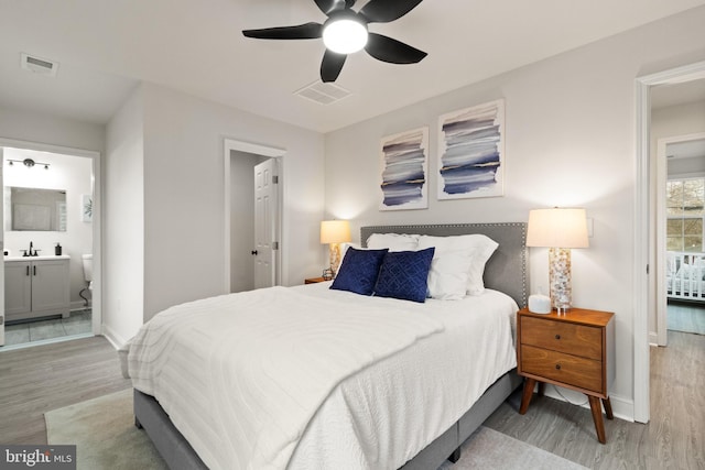 bedroom featuring baseboards, visible vents, wood finished floors, and ensuite bathroom