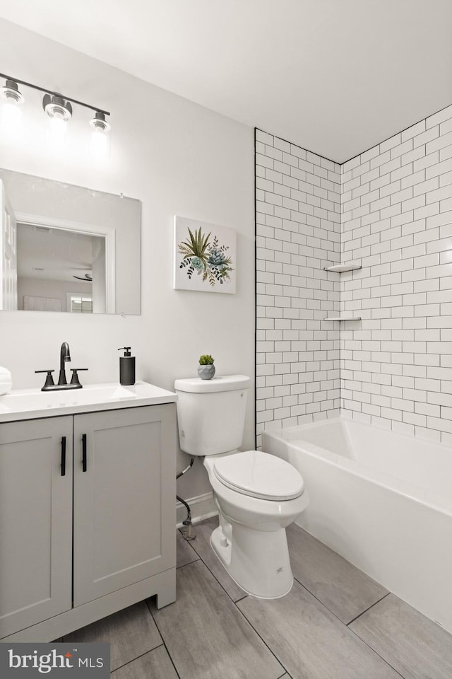 bathroom with shower / bathtub combination, wood finish floors, vanity, and toilet