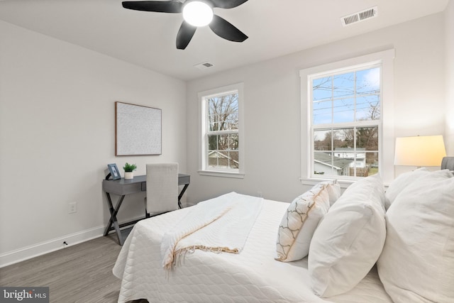 bedroom with ceiling fan, wood finished floors, visible vents, and baseboards