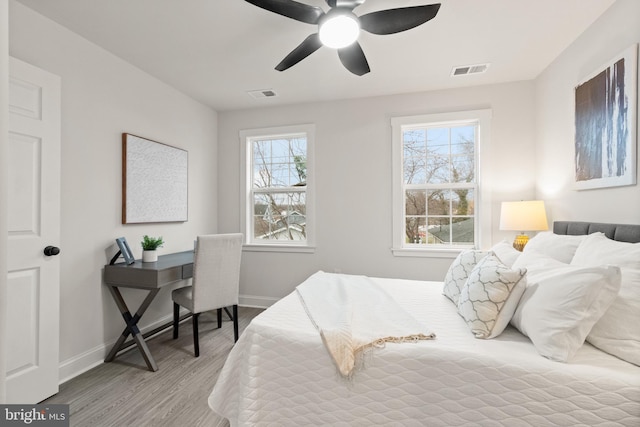 bedroom with baseboards, visible vents, and wood finished floors