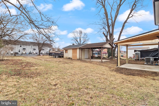 view of yard with an outbuilding, central AC, a carport, and a patio