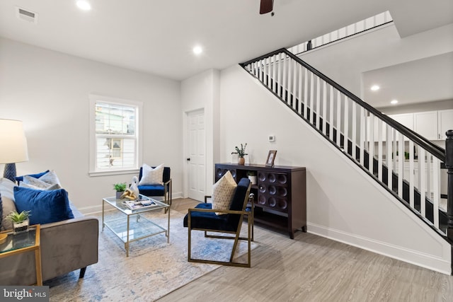 living area featuring wood finished floors, visible vents, baseboards, and stairs