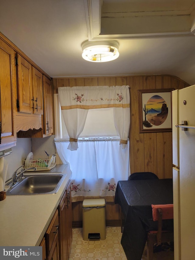 kitchen featuring wooden walls, sink, and white fridge