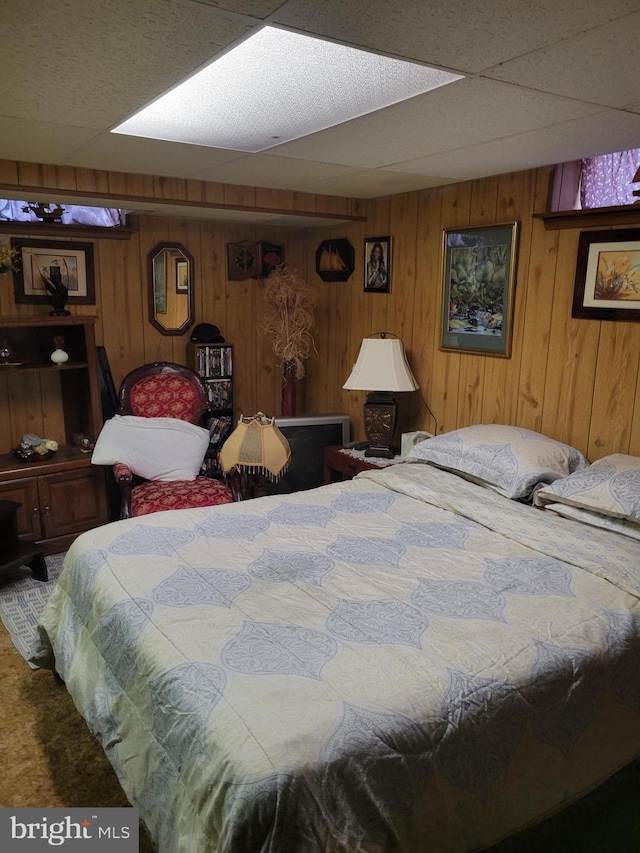 carpeted bedroom with a drop ceiling and wooden walls