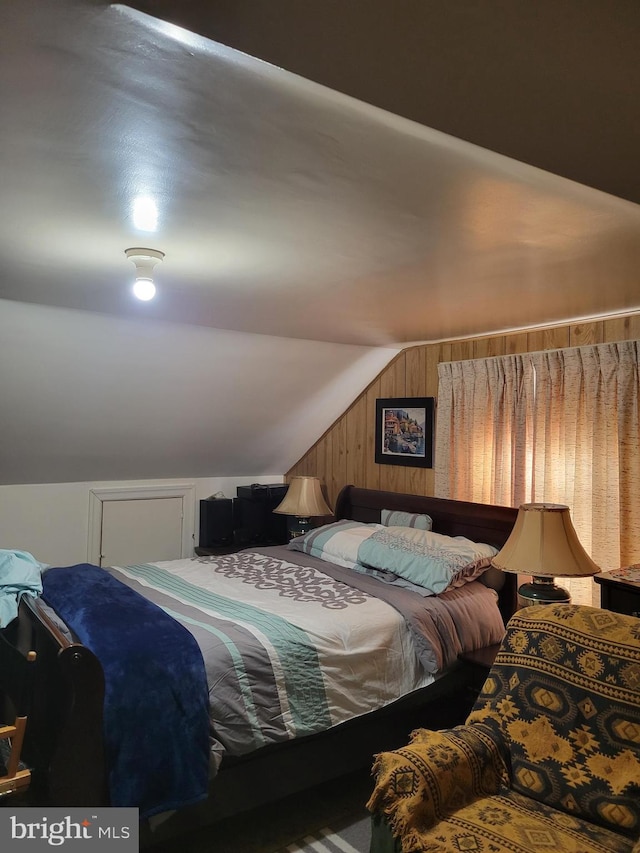 bedroom with lofted ceiling and wood walls