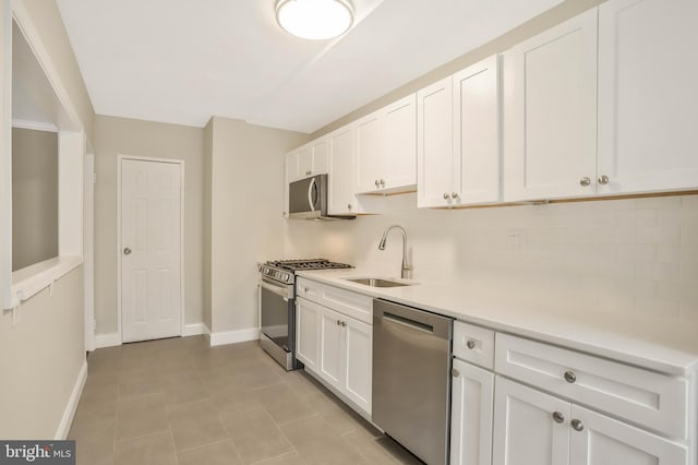 kitchen featuring sink, white cabinetry, light tile patterned floors, stainless steel appliances, and decorative backsplash