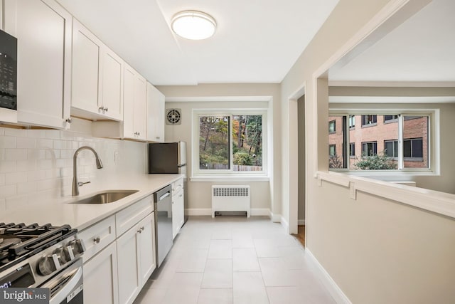 kitchen with radiator, stainless steel appliances, sink, and white cabinets