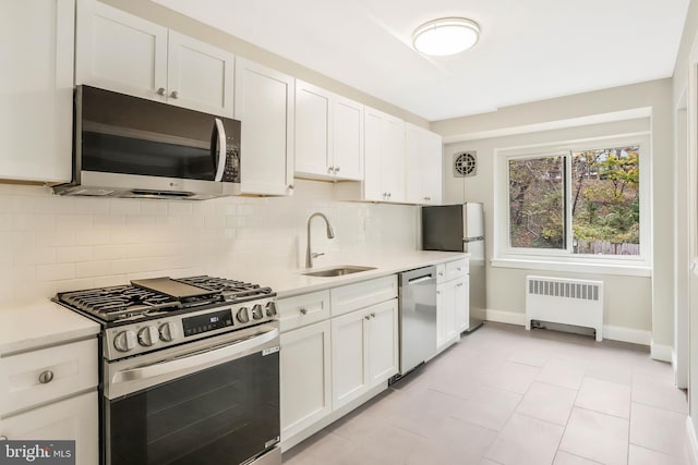 kitchen with white cabinetry, stainless steel appliances, and radiator heating unit