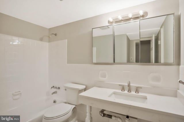 full bathroom with  shower combination, toilet, sink, and tile walls