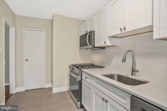 kitchen with appliances with stainless steel finishes, sink, white cabinets, and decorative backsplash