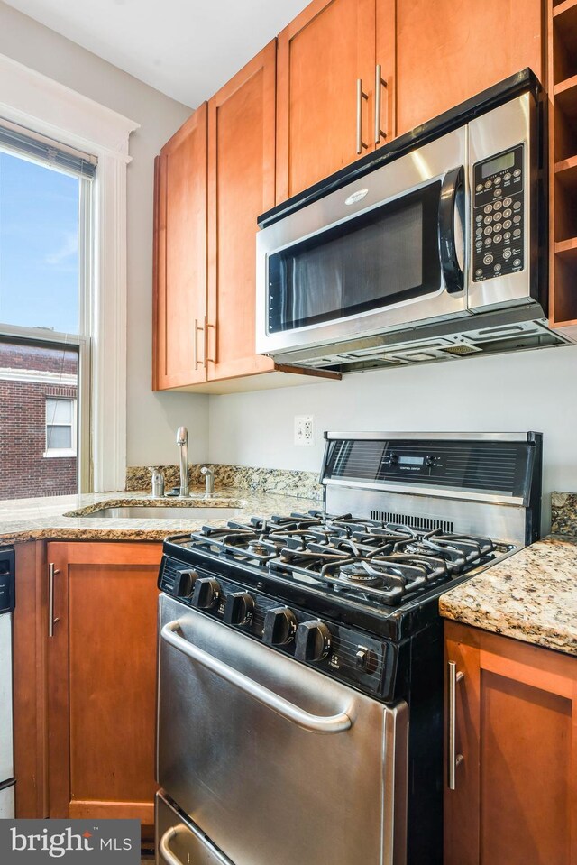 kitchen with sink, stainless steel appliances, and light stone countertops