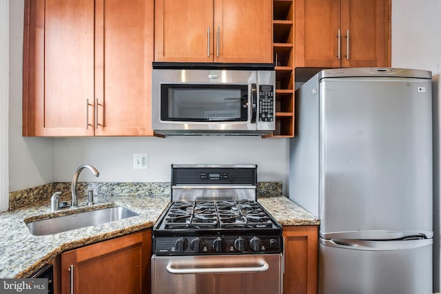 kitchen featuring appliances with stainless steel finishes, sink, and light stone counters