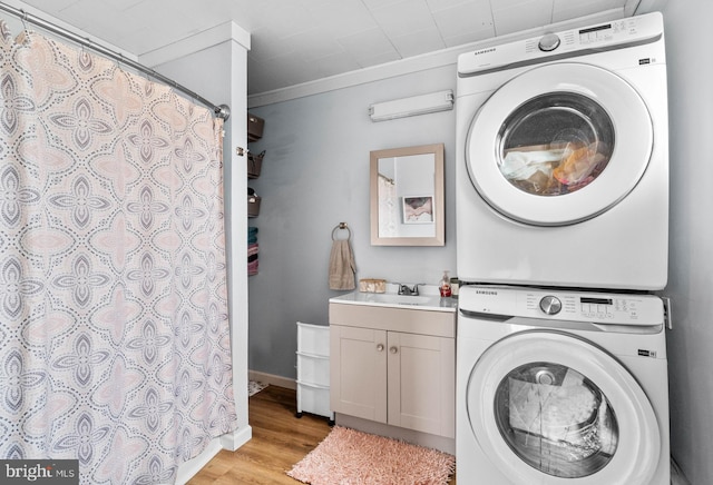 laundry area with stacked washer and dryer, sink, light hardwood / wood-style flooring, cabinets, and ornamental molding